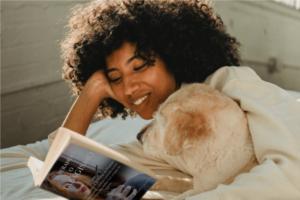 Mulher abraçada a seu cachorro lendo o e-Book Superando o Tabagismo